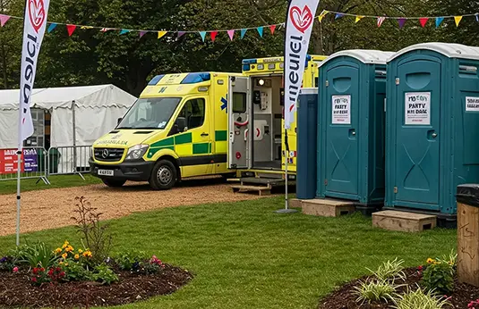 A scene showing an ambulance and portable toilets